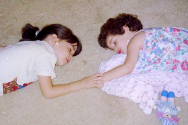 Young sisters fast asleep holding hands